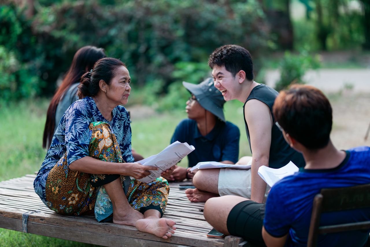 contact-img A diverse group enjoying a lively conversation outdoors on a sunny day.